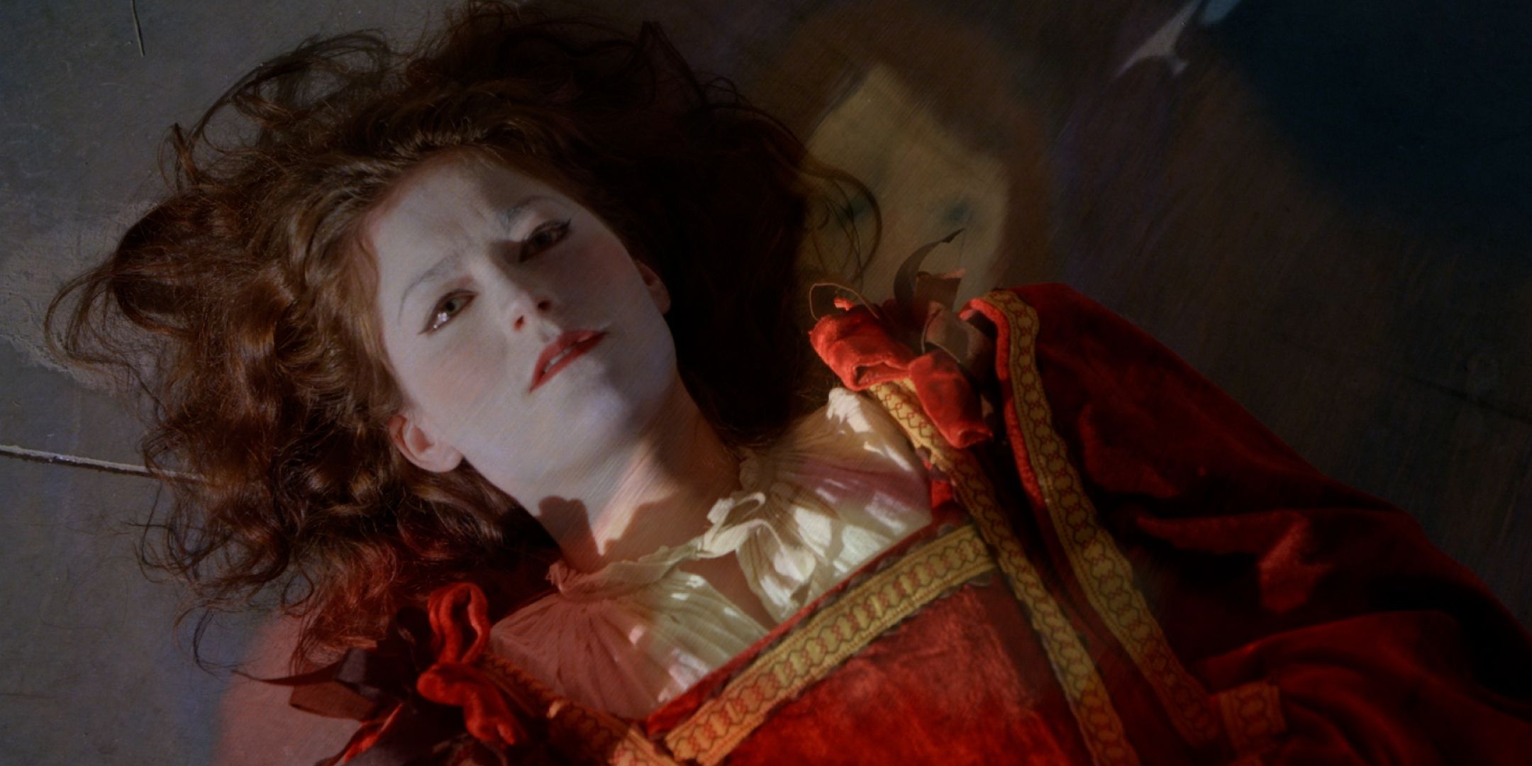 A woman dressed in a Renaissance dress and white face paint lies on the ground in Criminal Minds "Heathridge Manor."