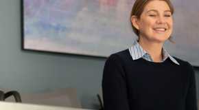 Meredith Grey (actor Ellen Pompeo) smiles in a blue sweater on Grey's Anatomy