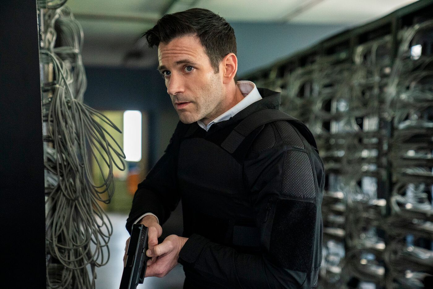 Brian Lange (actor Colin Donnell) holds his weapon approaching a suspect in FBI: International