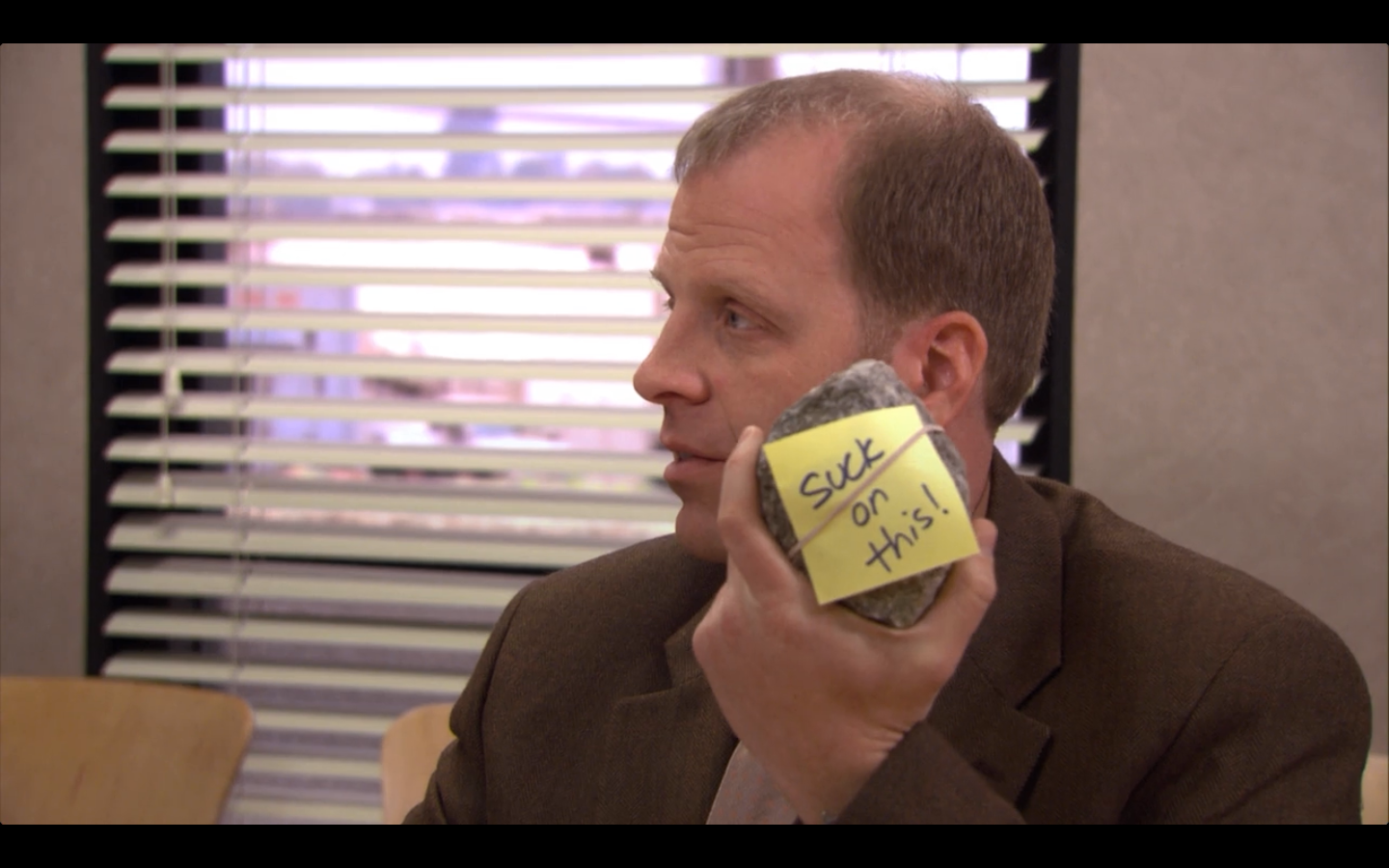 Toby holding a rock that Michael got him as a leaving gift on The Office.