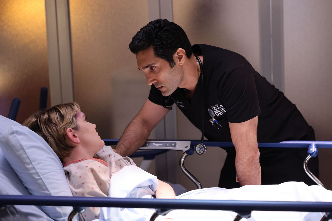 Dr. Crockett Marcel (actor Dominic Rains) leans over a patient's hospital bed on Chicago Med