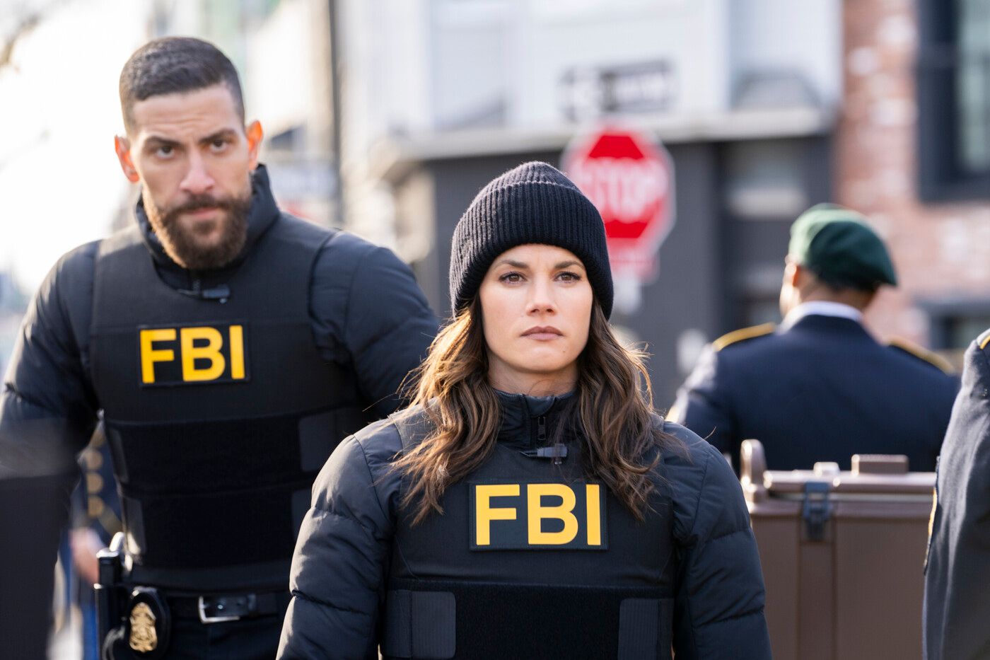 OA (actor Zeeko Zaki) walks behind Maggie (Missy Peregrym) in FBI vests in FBI