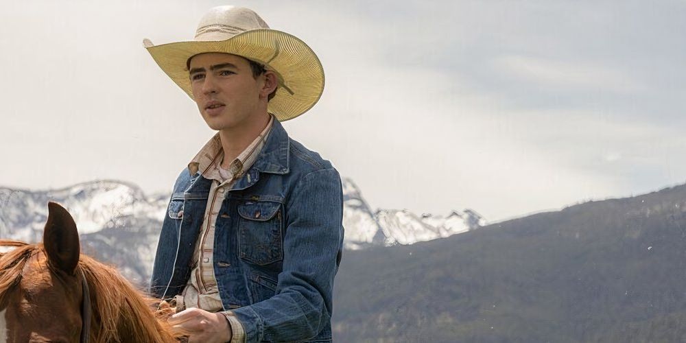 Carter (Finn Little) está andando a cavalo em Yellowstone com montanhas ao fundo.