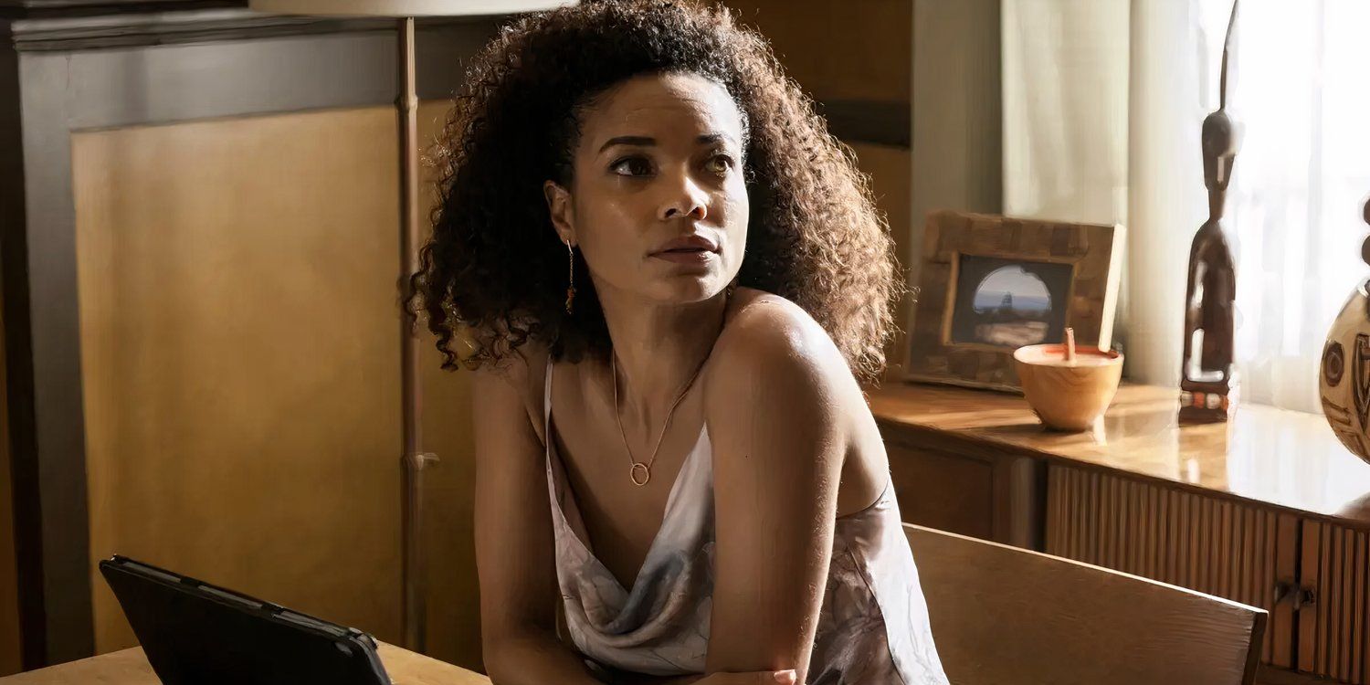 Nichelle Carmichael (Rochelle Aytes) sits at a desk with her arms crossed and looks to the right.