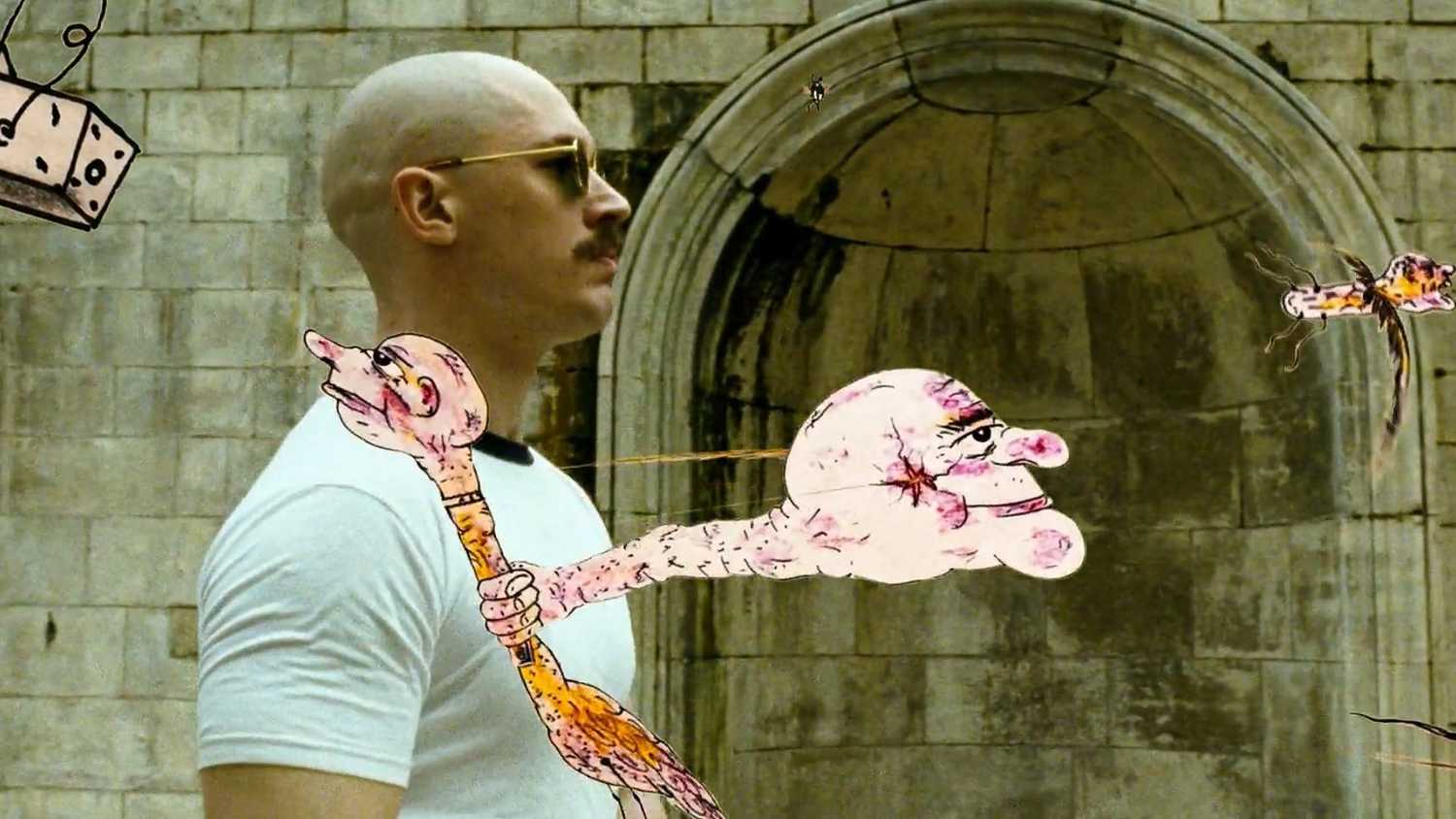 Tom Hardy as Charlie Bronson in his signature sunglasses walks as his drawings fly around him in Bronson