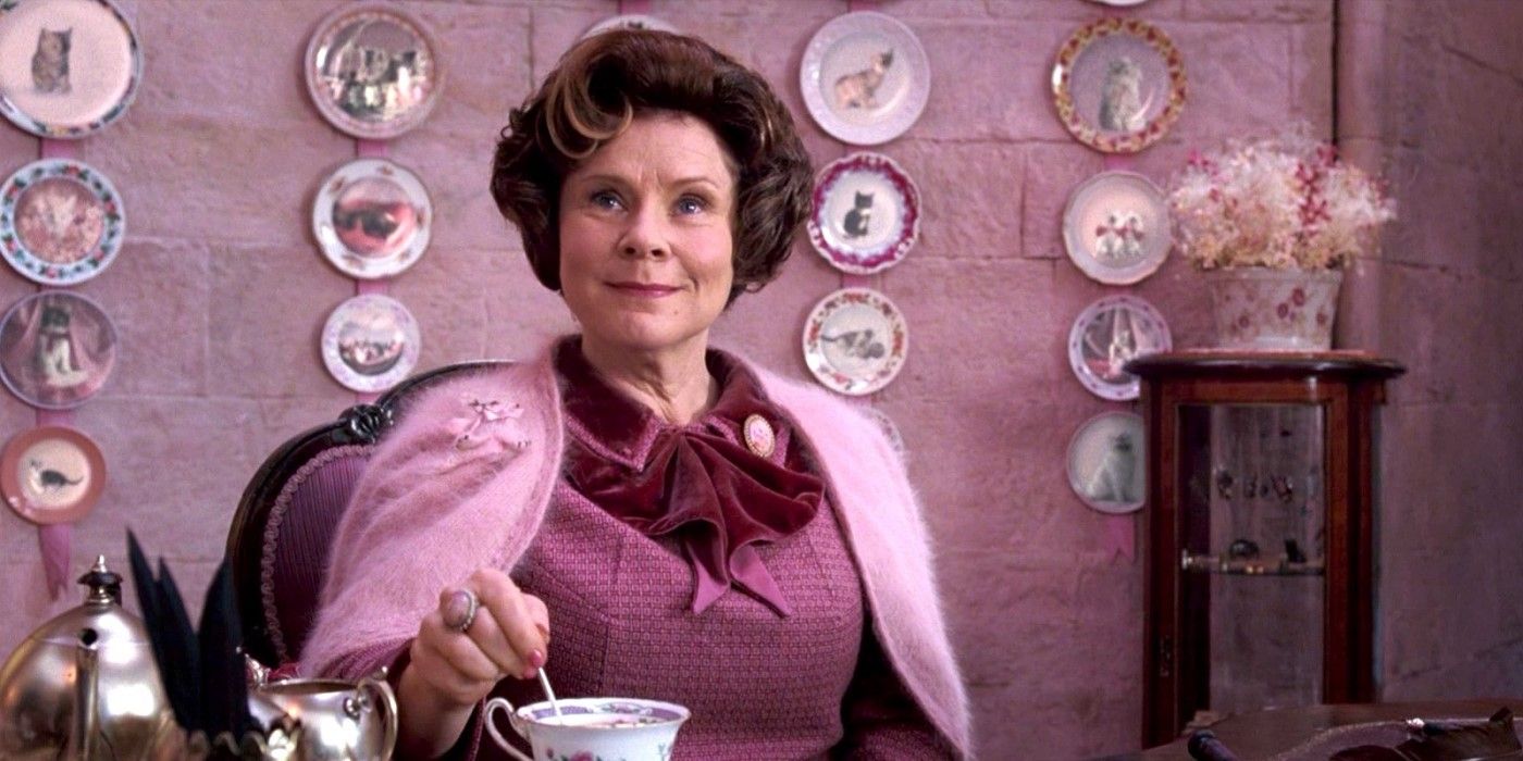 Dolores Umbridge behind a desk in her study surrounded by cat plates