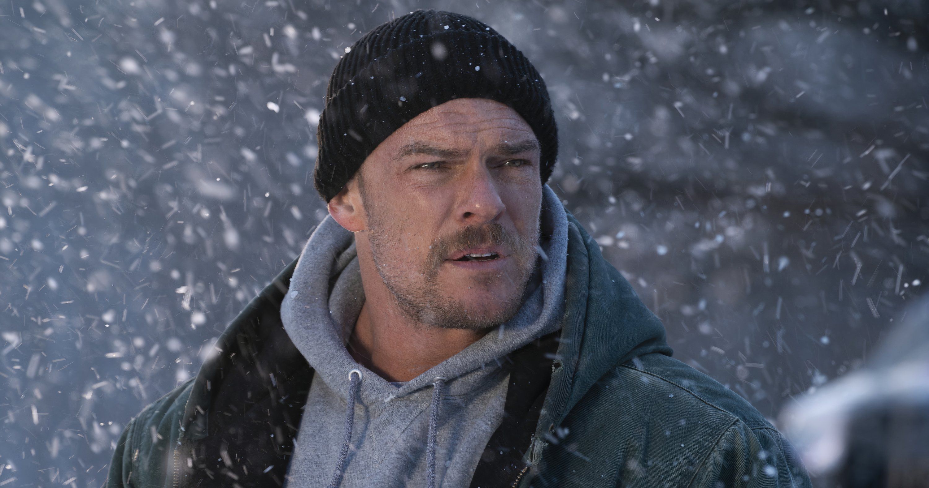 Alan Ritchson standing in the snow in Ordinary Angels