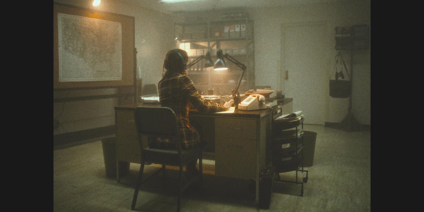 Young Ann Burgess seen from behind working at her desk in Hulu's Mastermind: To Think Like a Killer