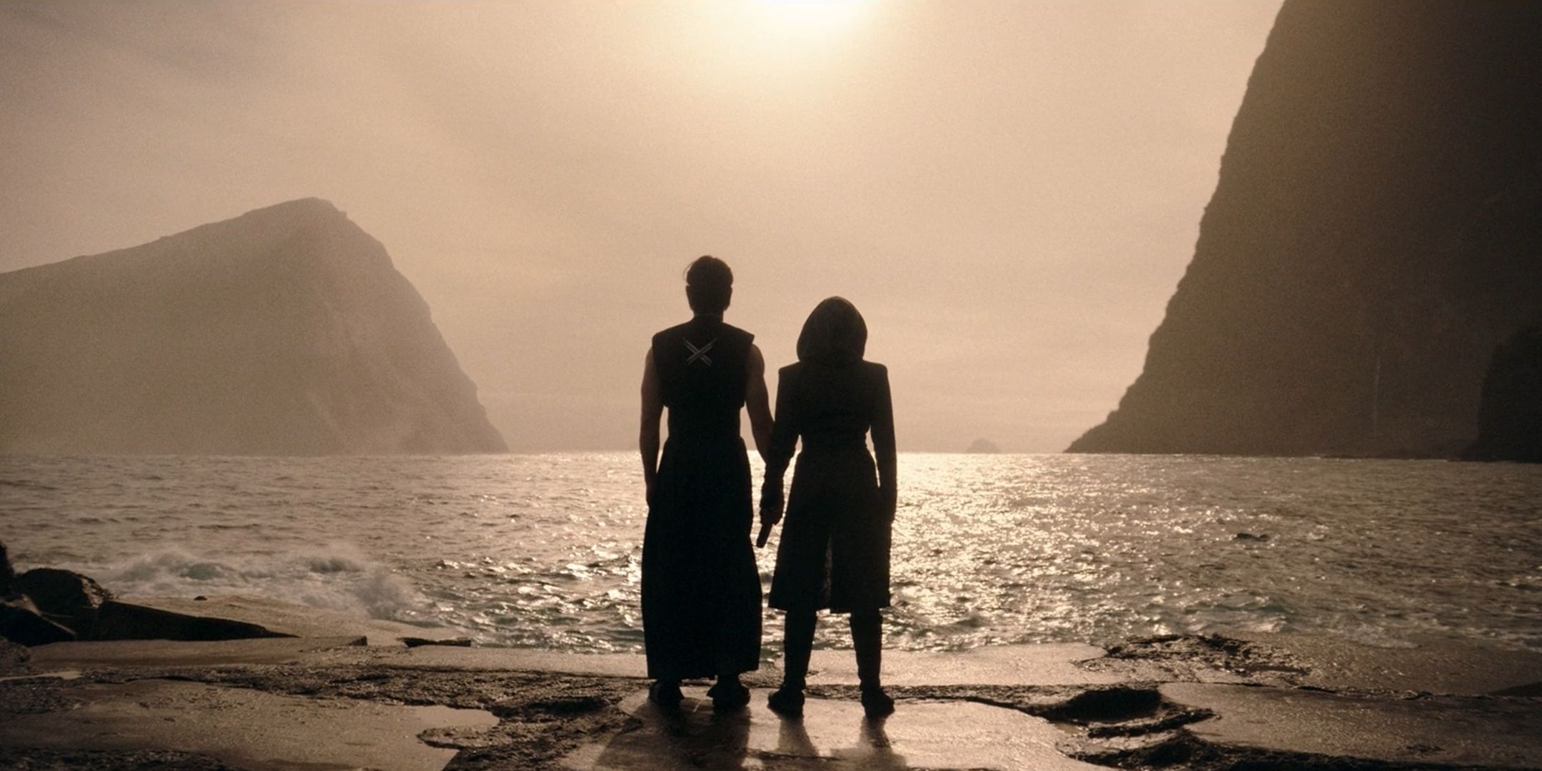 Qmir and Osha, back to camera, looking out over an ocean holding hands from The Acolyte