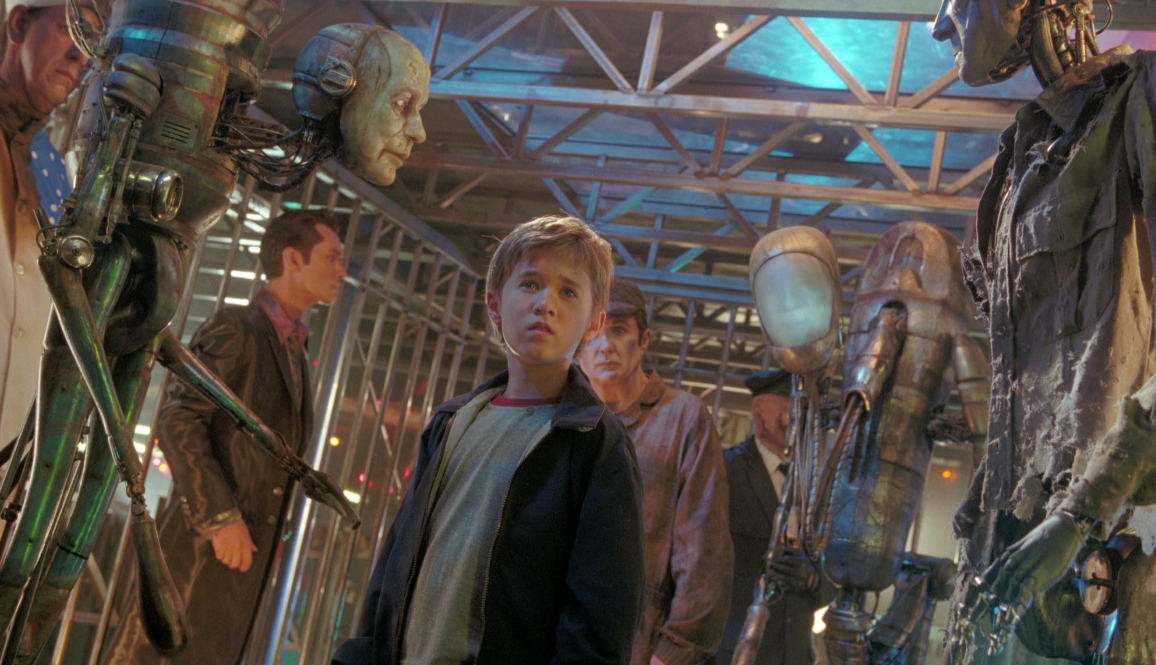 David stands in a room of older versions of Mechas in A.I. Artificial Intelligence.