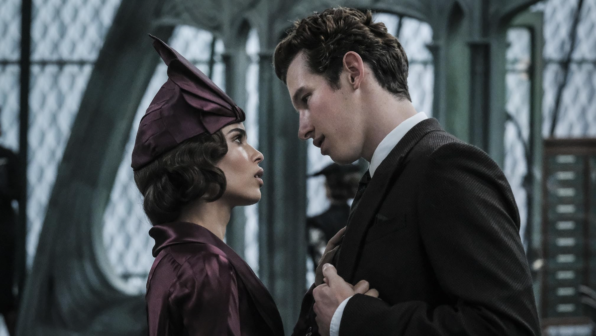 Deixe e Teseu dar as mãos e olhar um para o outro em trajes formais nos Crimes de Grindelwald.