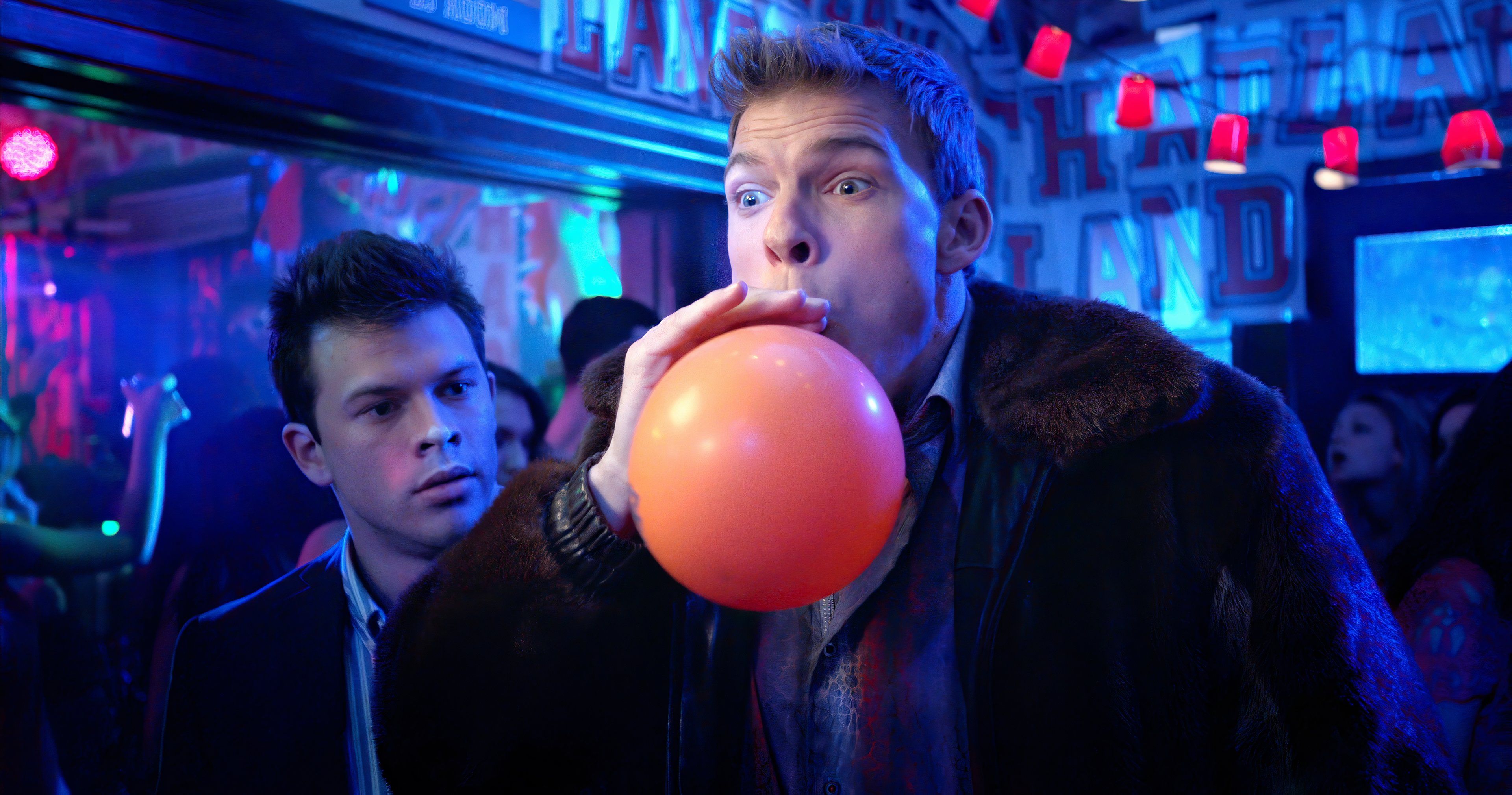 Thad Castle is blowing up a balloon at a party in Blue Mountain State