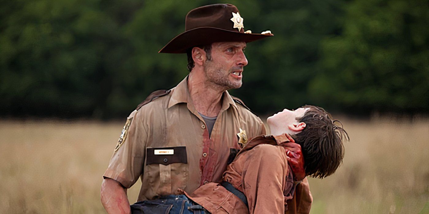 Rick in his sheriff uniform holding a limp Carl on The Walking Dead.