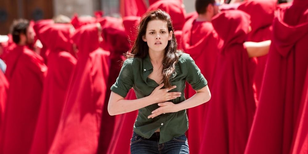 Bella runs through a crowd of people in red cloaks. 