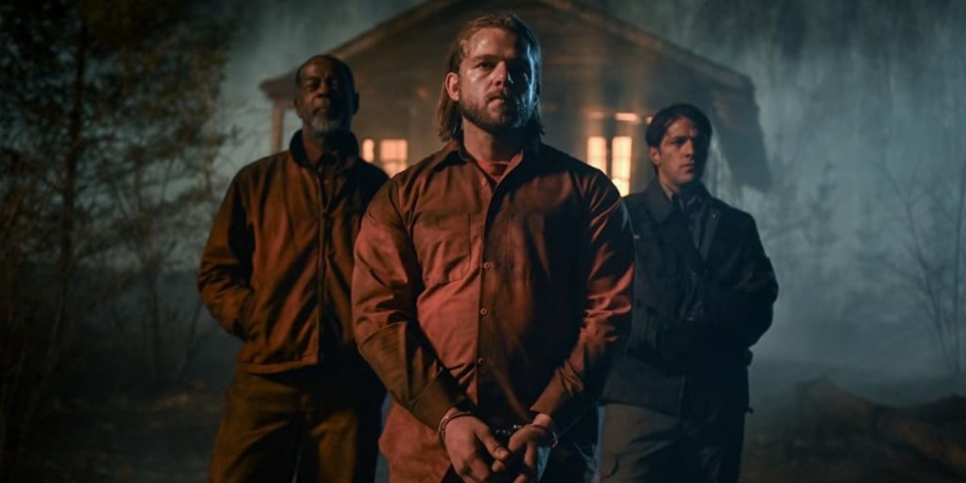 Max Thieriot as Bode Leone stands in front of a cabin in the woods with Alex Désert as Rudy and Alberto Frezza as Andy Kubiak behind him on Fire Country