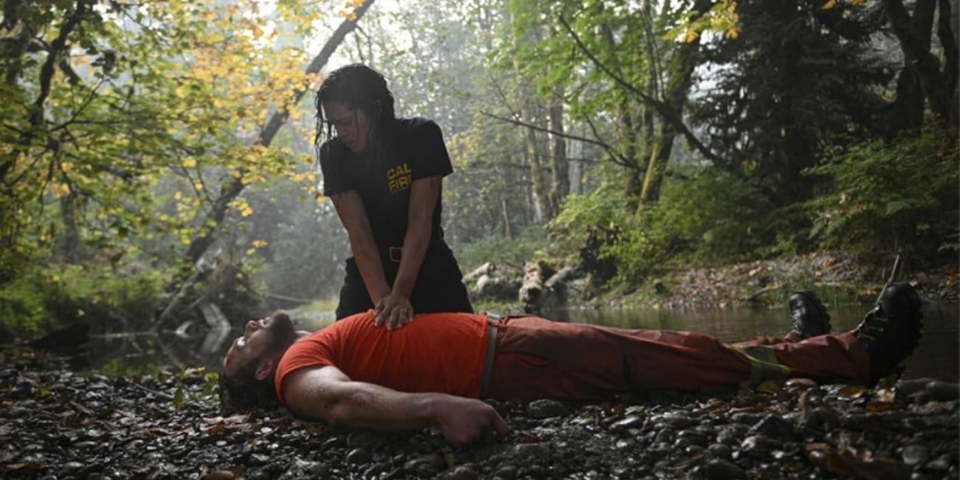 Stephanie Arcila as Gabriela Perez performs CPR on Max Thieriot as Bode Leone next to the river on Fire Country