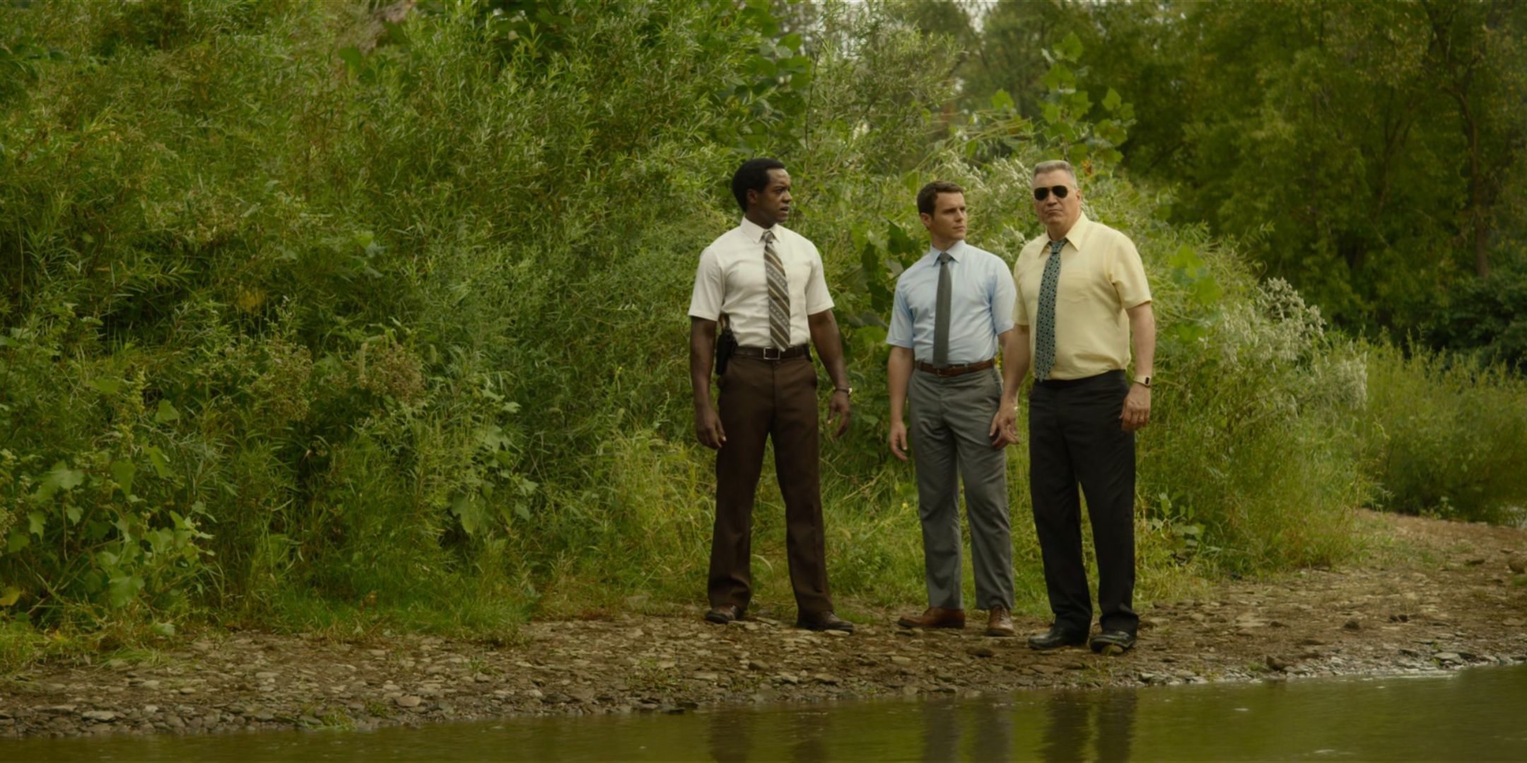 Albert Jones as Jim Barney, Jonathan Groff as Holden Ford and Holt McCallany as Bill Tench stand at the edge of a river in Mindhunter