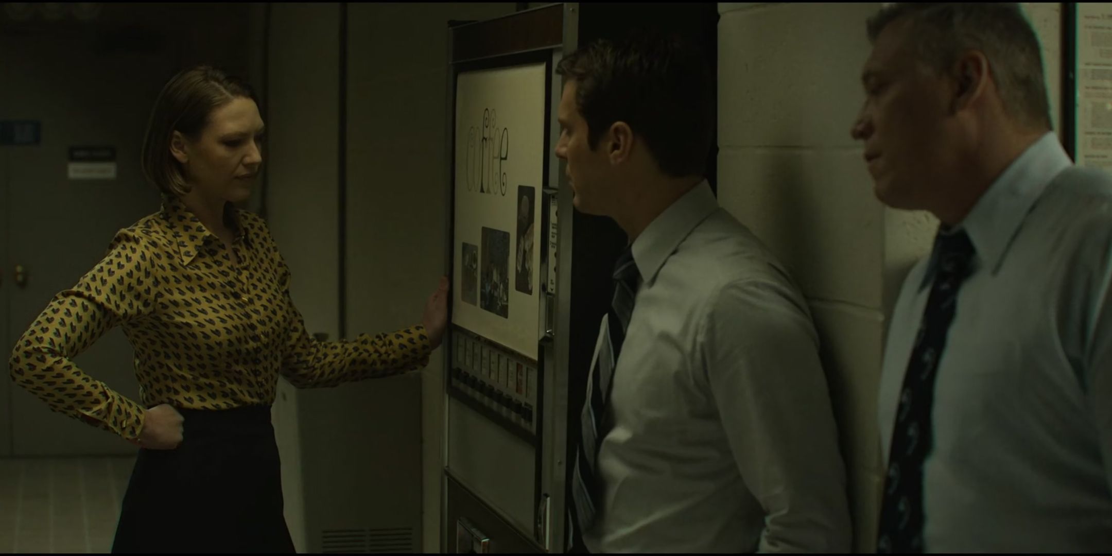 Anna Torv as Wendy Carr gets coffee from a machine as she talks to Jonathan Groff as Holden Ford and Holt McCallany as Bill Tench in Mindhunter