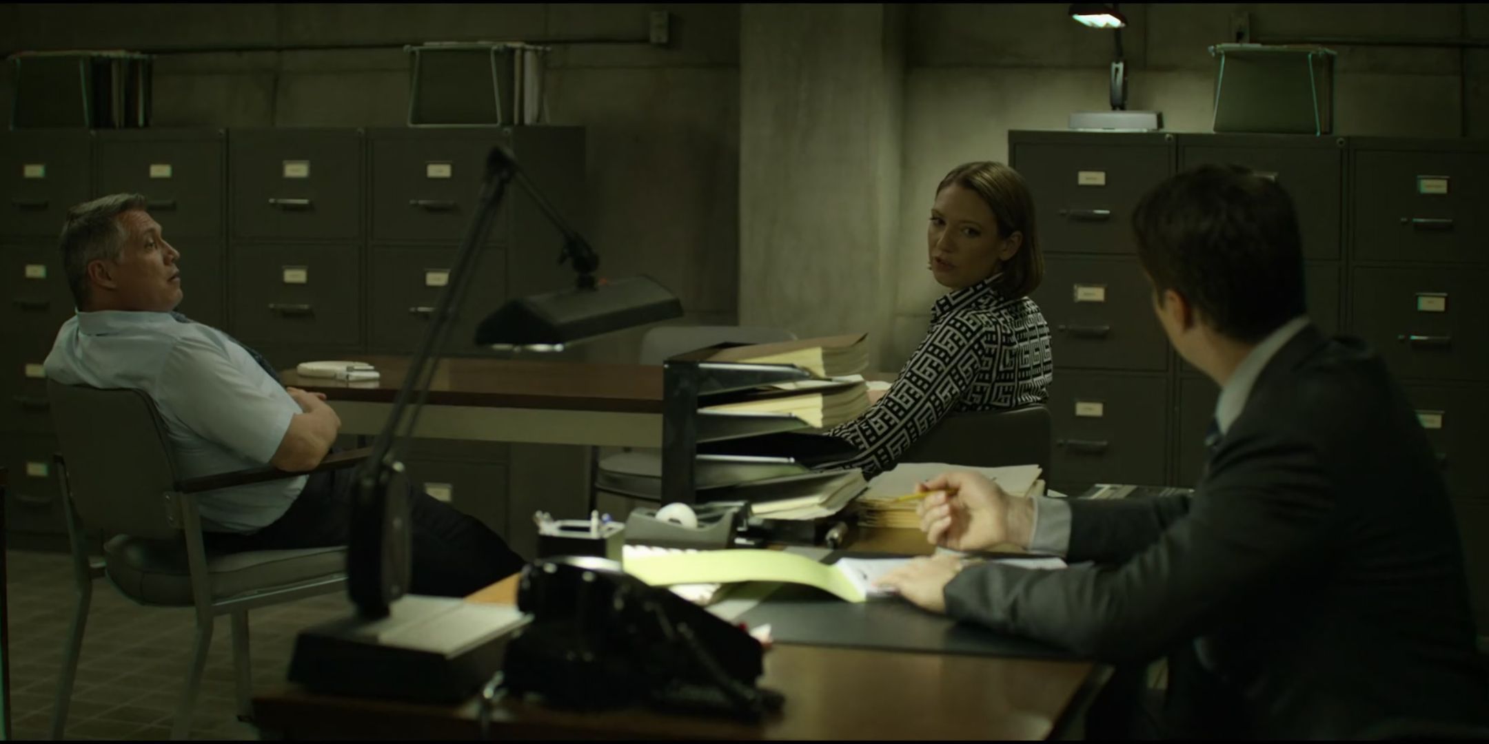 Anna Torv as Wendy Carr looks over her shoulder and talks to Jonathan Groff as Holden Ford as Holt McCallany as Bill Tench looks on in the Quantico office in Mindhunter