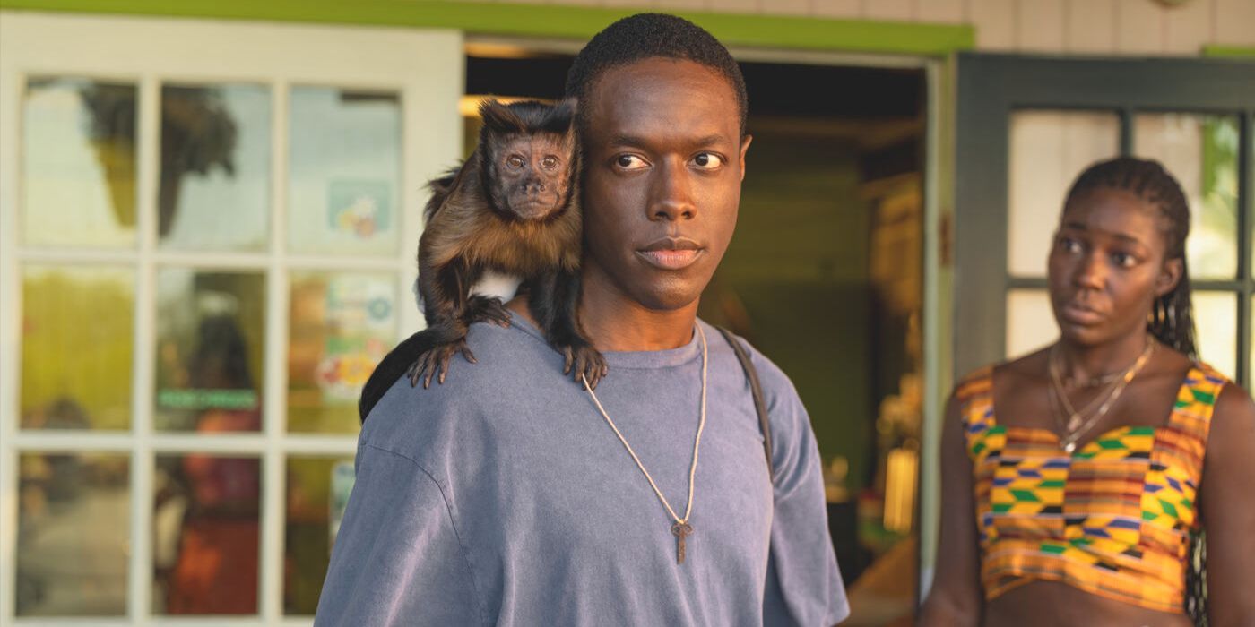 Neville (actor Ronald Peet) stands on a porch with a monkey on his shoulder in Apple TV's 