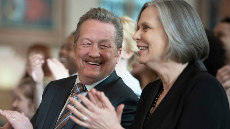 Christian Stolte as Randall 'Mouch' McHolland smiles at Amy Morton as Trudy Platt while they sit in a crowd and clap on Chicago Fire