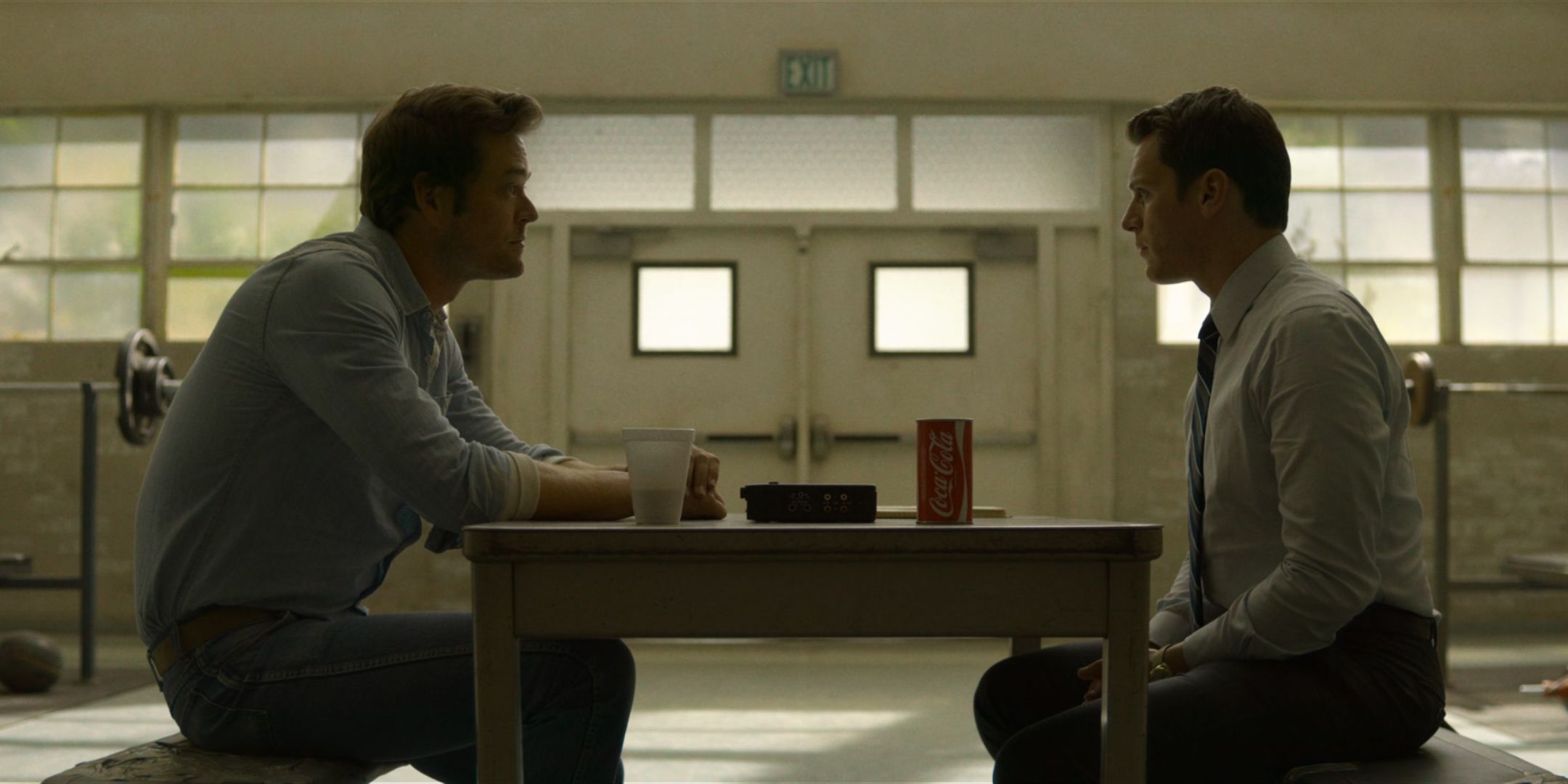 Christopher Backus as Tex Watson sits at a prison table and talks to Jonathan Groff as Holden Ford in Mindhunter