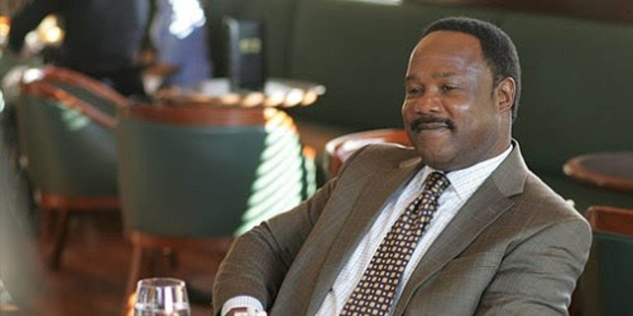 Clay Davis de The Wire, interpretado por Isiah Whitlock Jr., sentado en un restaurante sonriendo para sí mismo