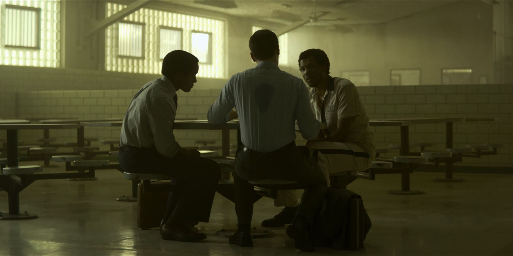 Corey Allen as William Henry Hance sits at a prison table and talks to Jonathan Groff as Holden Ford and Albert Jones as Jim Barney in Mindhunter