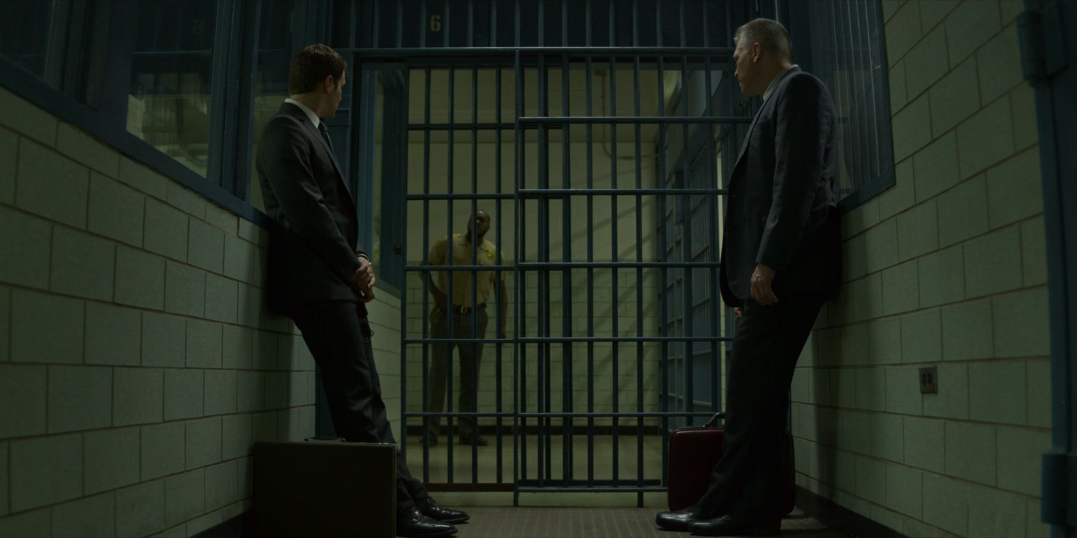 Jonathan Groff as Holden Ford and Holt McCallany as Bill Tench lean against a wall in front of prison bars in Mindhunter