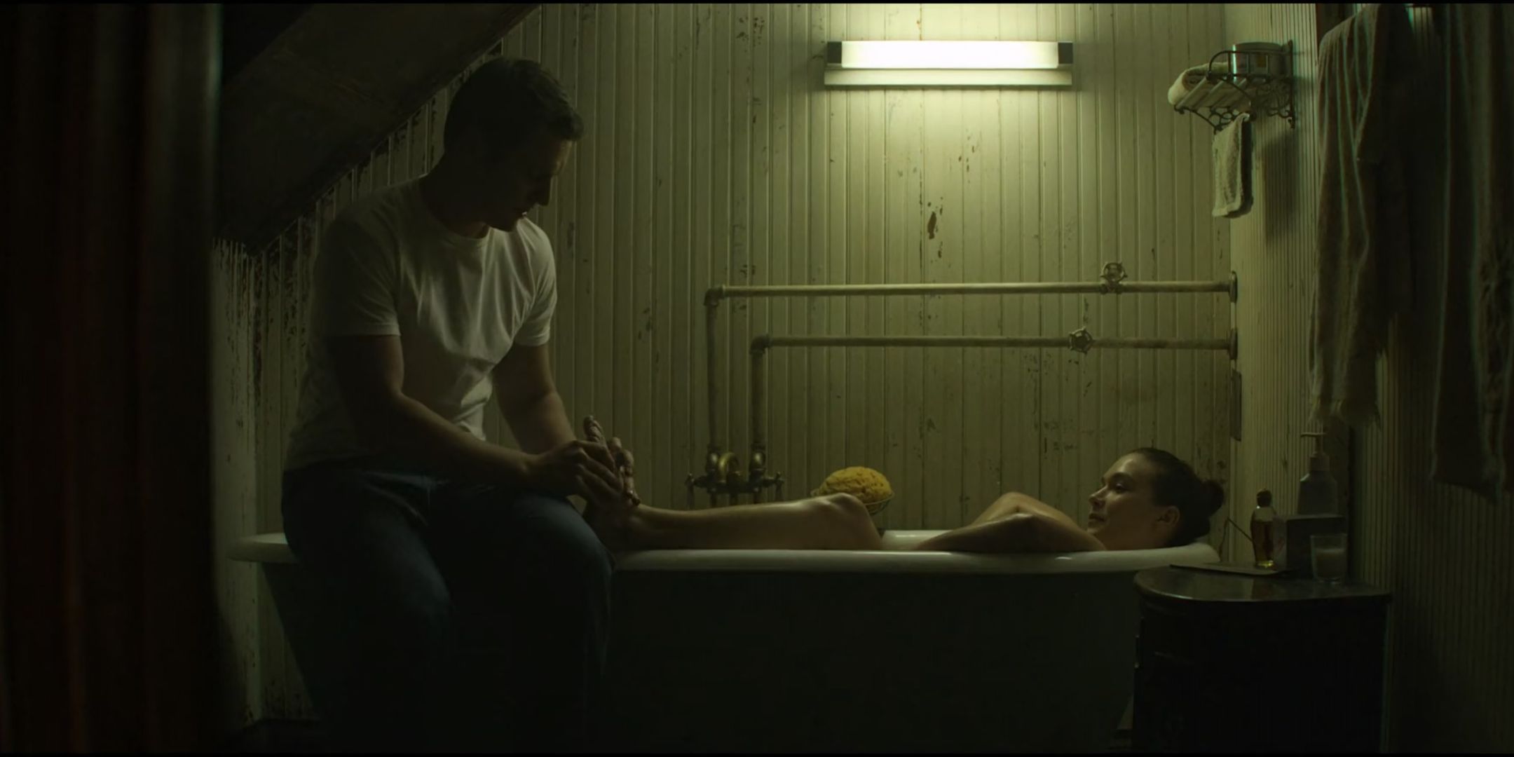 Jonathan Groff as Holden Ford rubs the feet of Hannah Gross as Debbie Mitford who is in a bath in Mindhunter