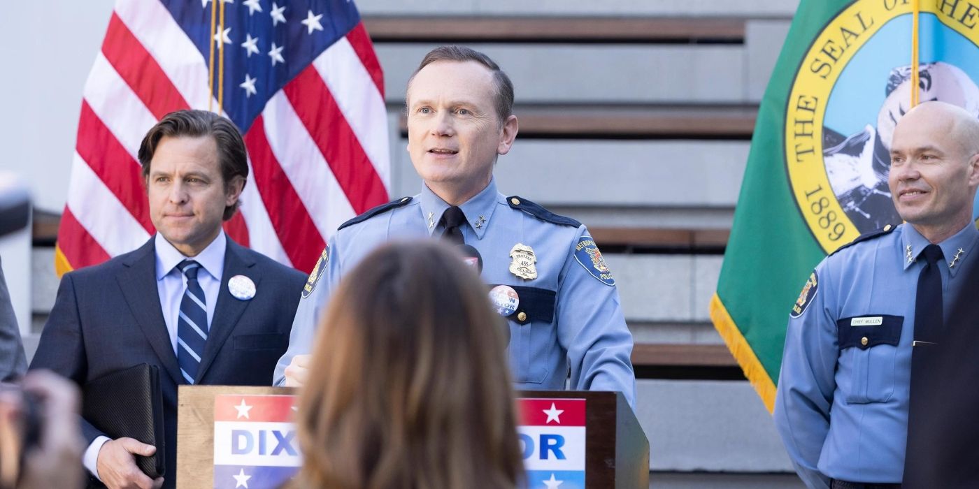 Pat Healy as Michael Dixon stands behind a podium in his police uniform on Station 19