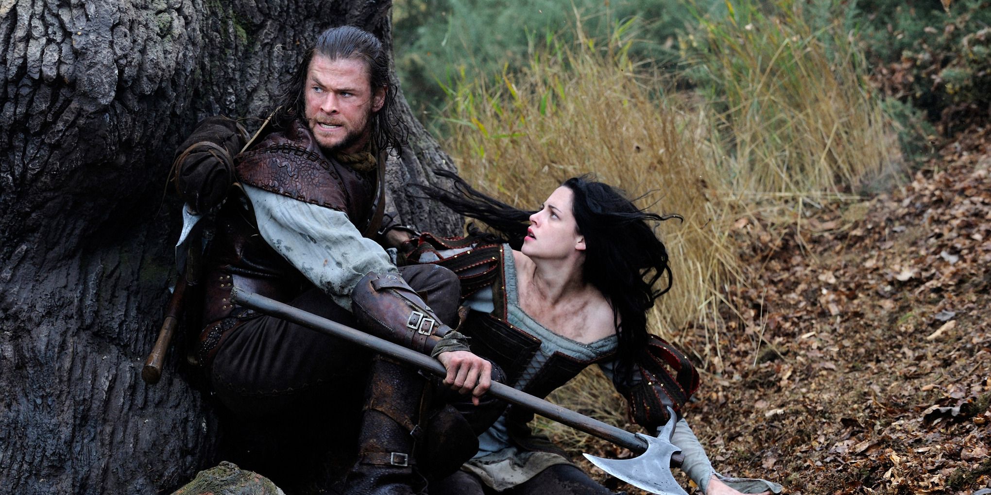 Kristen Stewart as Snow White and Chris Hemsworth as the Huntsman crouching in the woods from Snow White and the Huntsmen