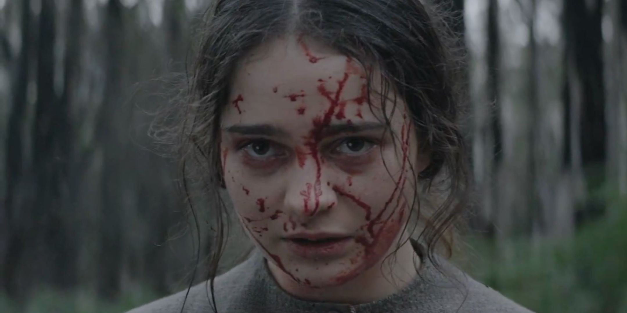 Aisling Franciosi like Clare Carroll Glares with blood on his face in Rossignol
