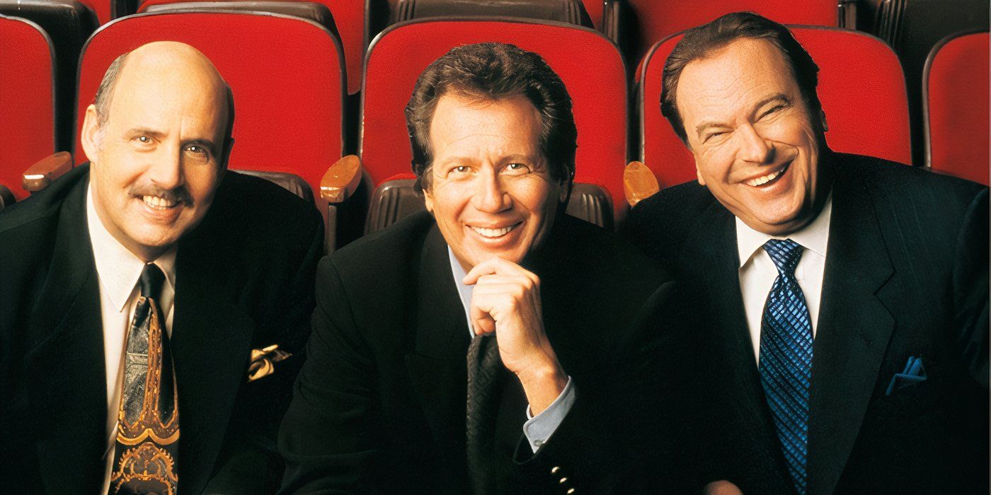 Larry Sanders (Garry Shandling), Hank Kingsley (Jeffrey Tambor) e Artie (Rip Tom) estão sentados em cadeiras e sorrindo.