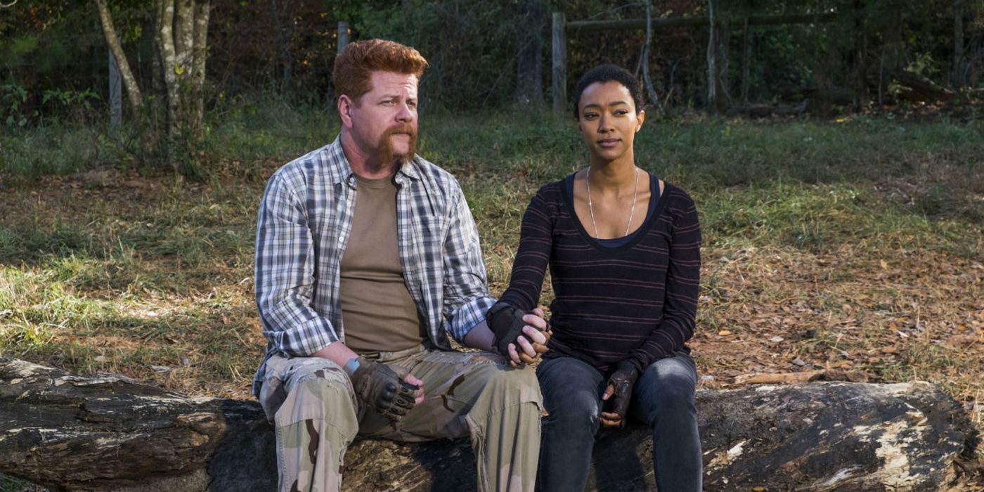 Abraham and Sasha sitting on a rock holding hands in The Walking Dead.