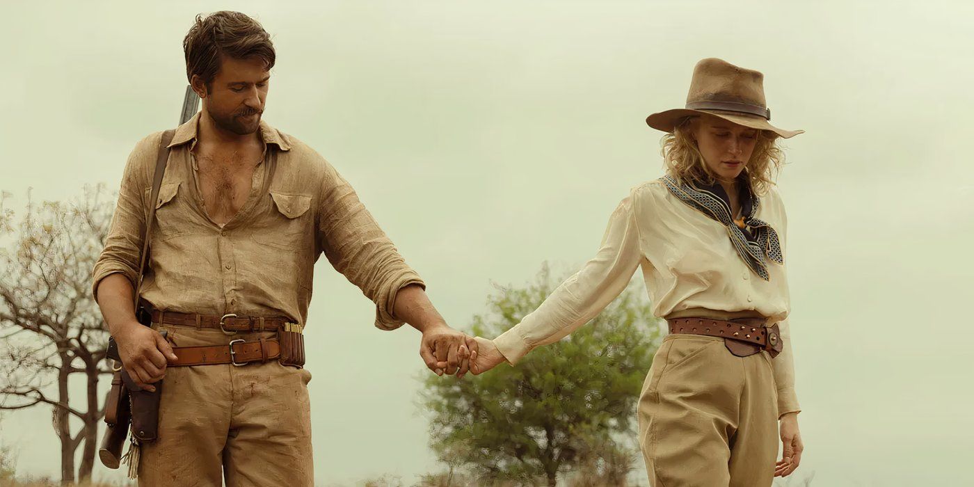 Brandon Sklenar as Spencer Dutton and Julia Schlaepfer as Alexandra walking through the plains of Africa together after meeting on an excursion in 1923.