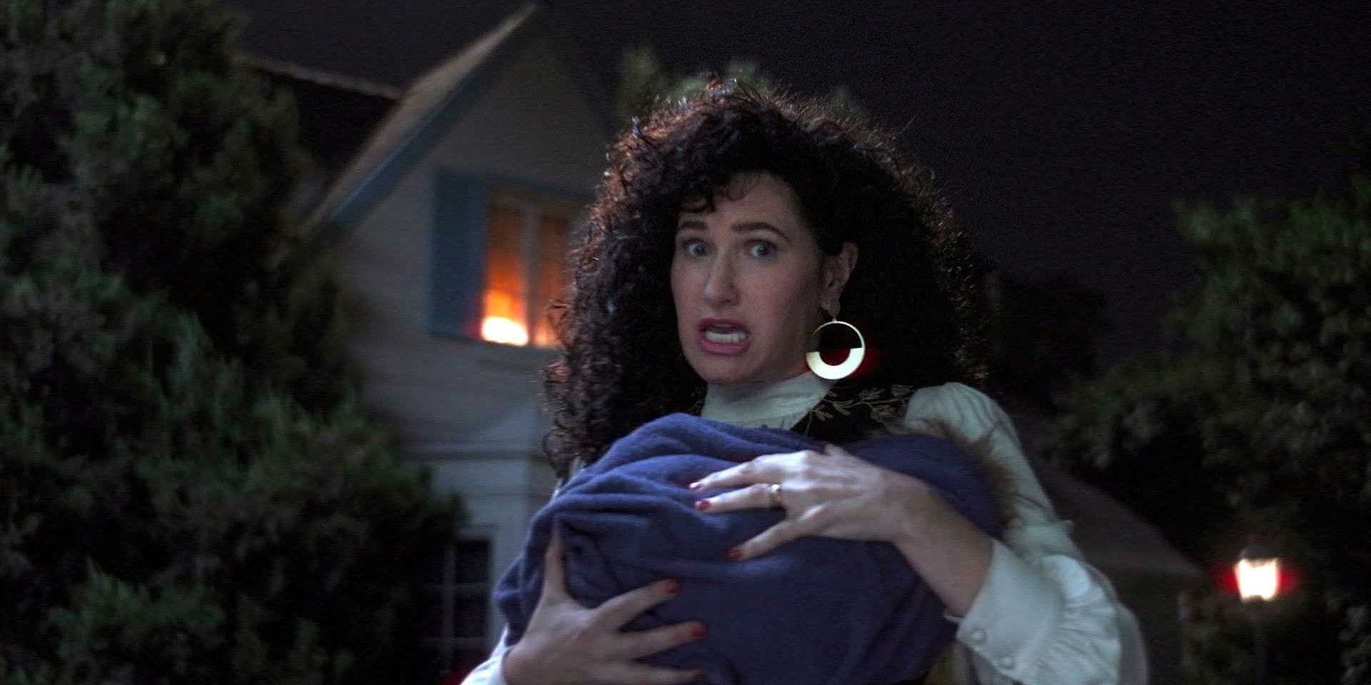 Agatha Harkness in 80s outfit holding a deceased Sparky in WandaVision.