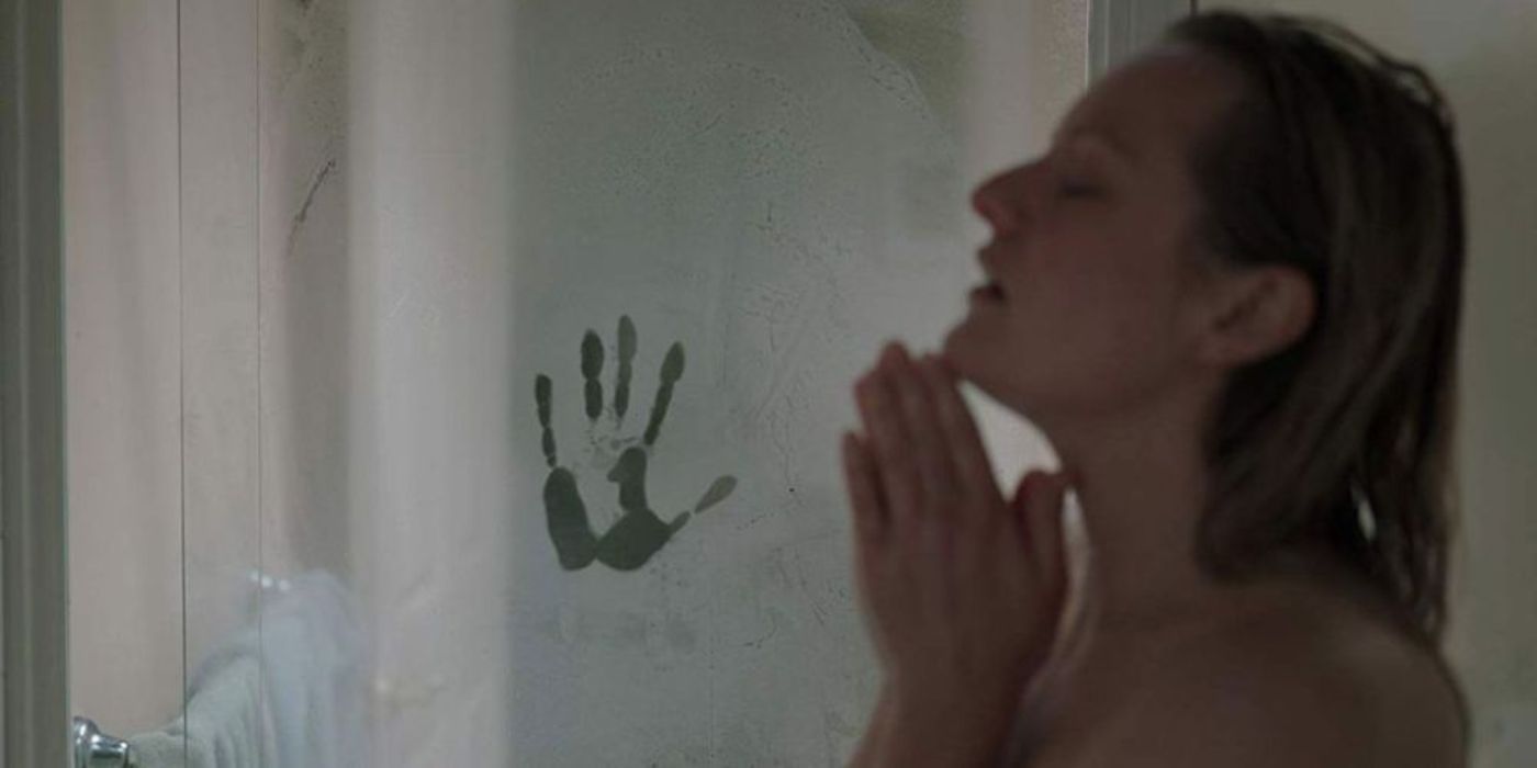 Cecelia (Elisabeth Moss) is showering when a handprint appears in the fog on the glass door.