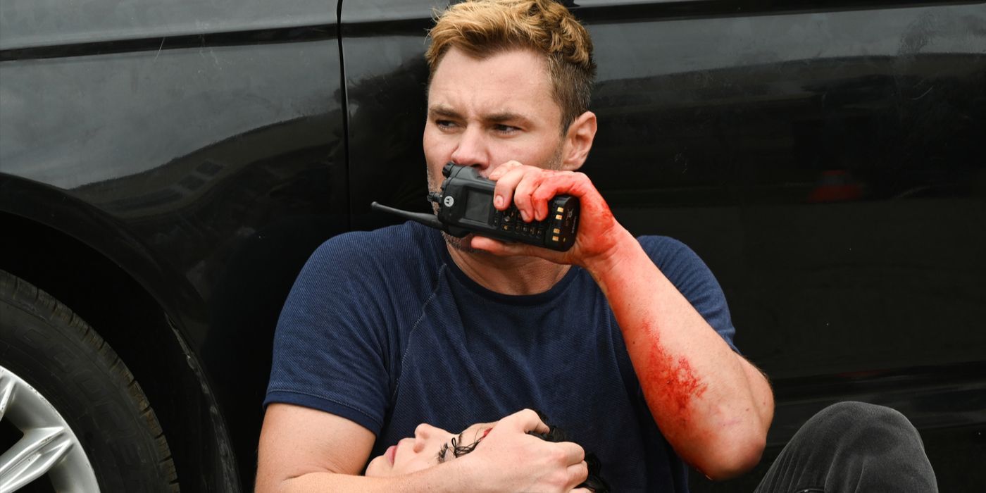 A bloodied Adam Ruzek speaks into a radio while holding his wounded partner in Chicago PD Season 12