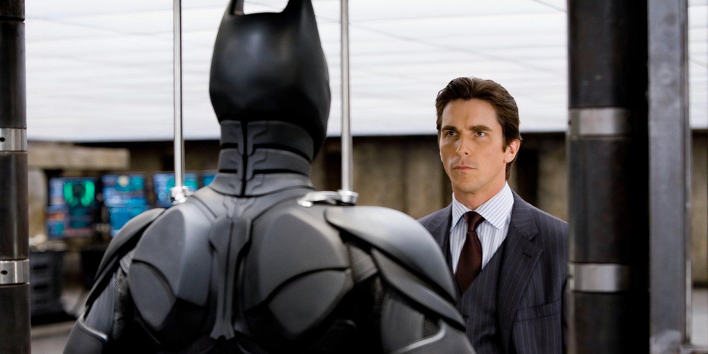 Christian Bale como Bruce Wayne olhando para seu traje do Batman antes de guardá-lo por um tempo em O Cavaleiro das Trevas.