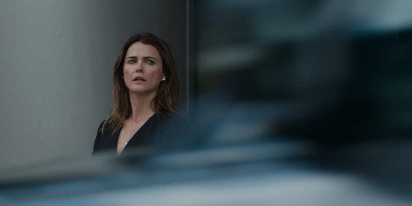 Kate Wyler, played by Keri Russell, looks out from behind a parked car in The Diplomat Season 2