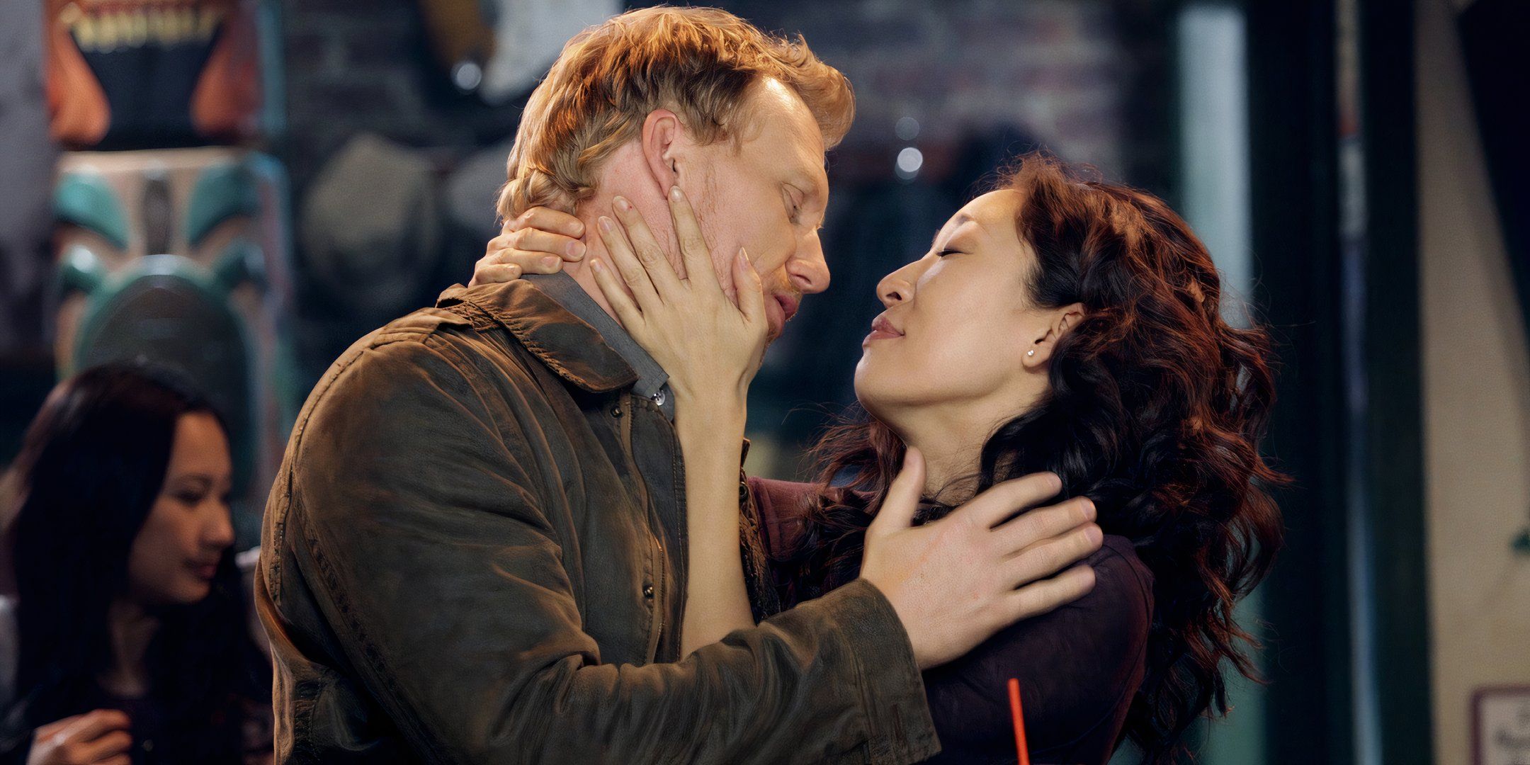 Owen Hunt and Cristina Yang caressing each other as they lean in for a kiss at Joe's Bar in Grey's Anatomy.