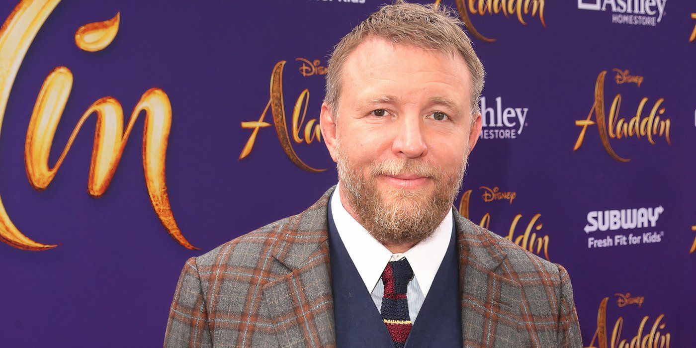 Guy Ritchie stands on the Aladdin red carpet and has his photo taken