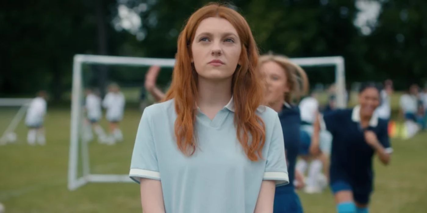 Harriet Manners (Emily Carey) contemplates while her classmates play football/soccer behind her in Geek Girl