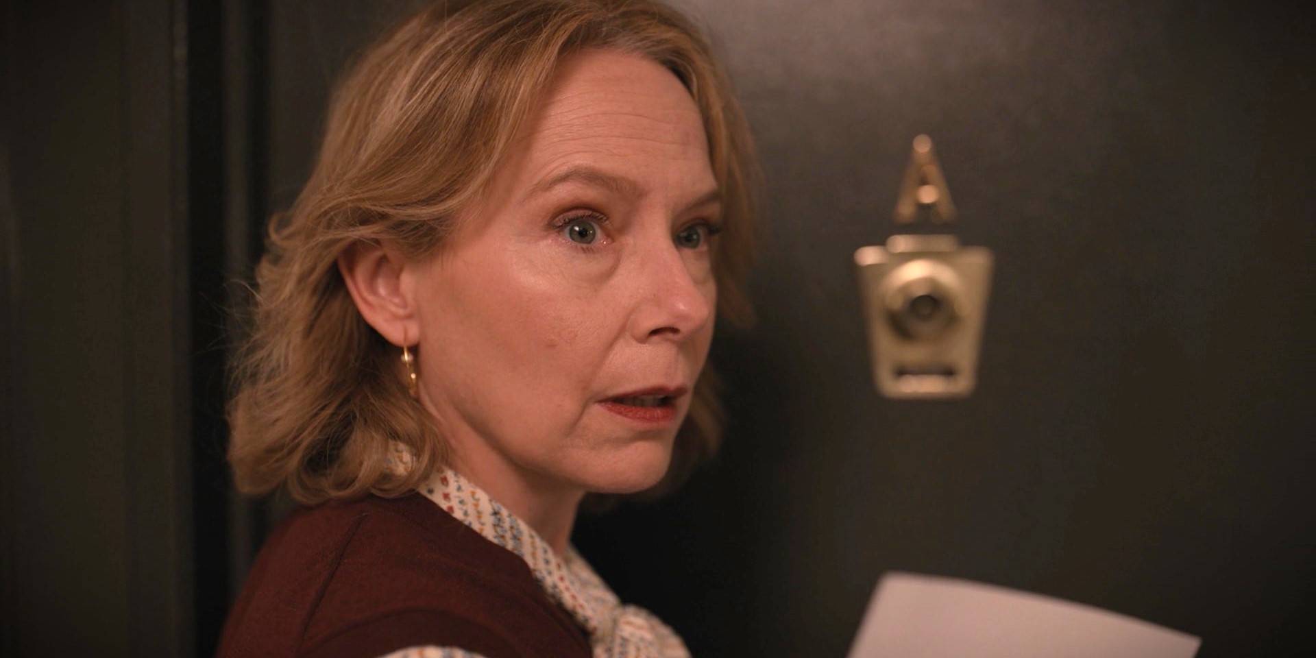 Jan Bellows is standing outside her apartment holding a note in Only Murders in the Building Season 1.