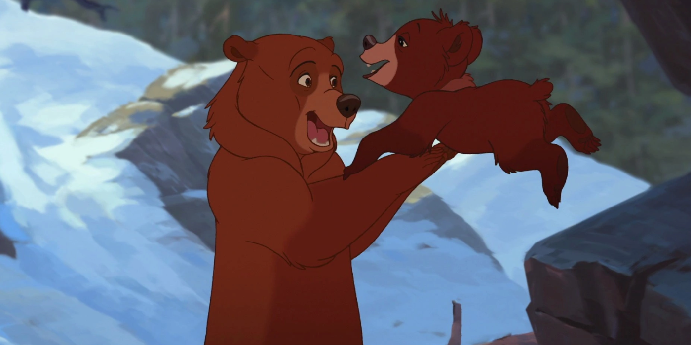 Bear Kenai está pegando Koda enquanto Koda pula de uma saliência de pedra em uma caverna de geleira em Brother Bear.