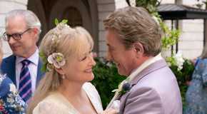 Loretta and Oliver looking at one another and embracing on their wedding day in Only Murders in the Building.