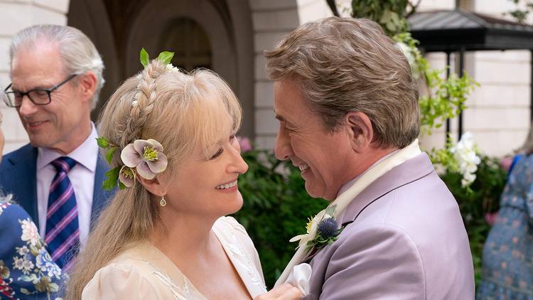 Loretta and Oliver looking at one another and embracing on their wedding day in Only Murders in the Building.