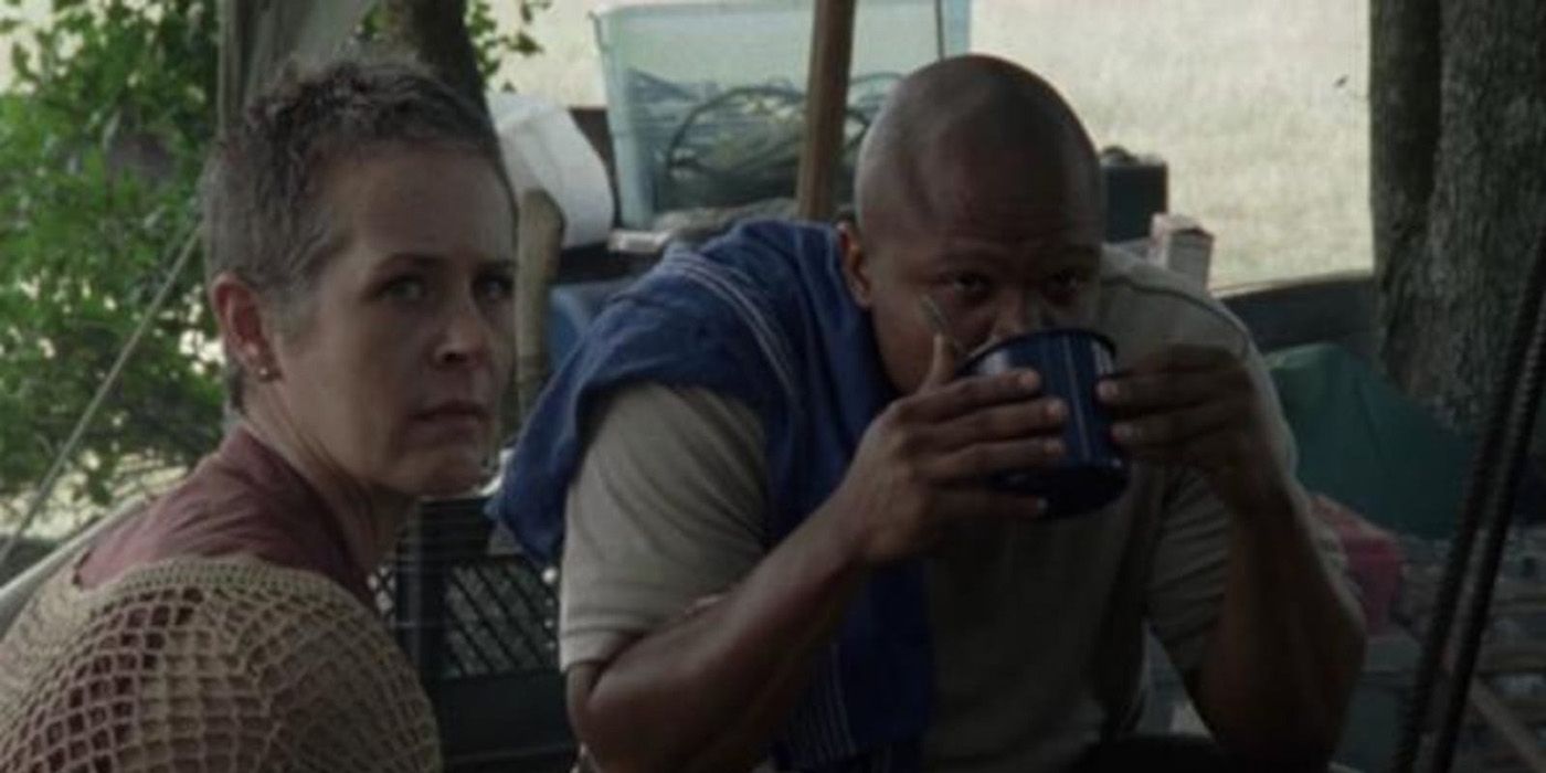 Carol sitting with T-Dog in The Walking Dead looking back while he sips on something in a mug.