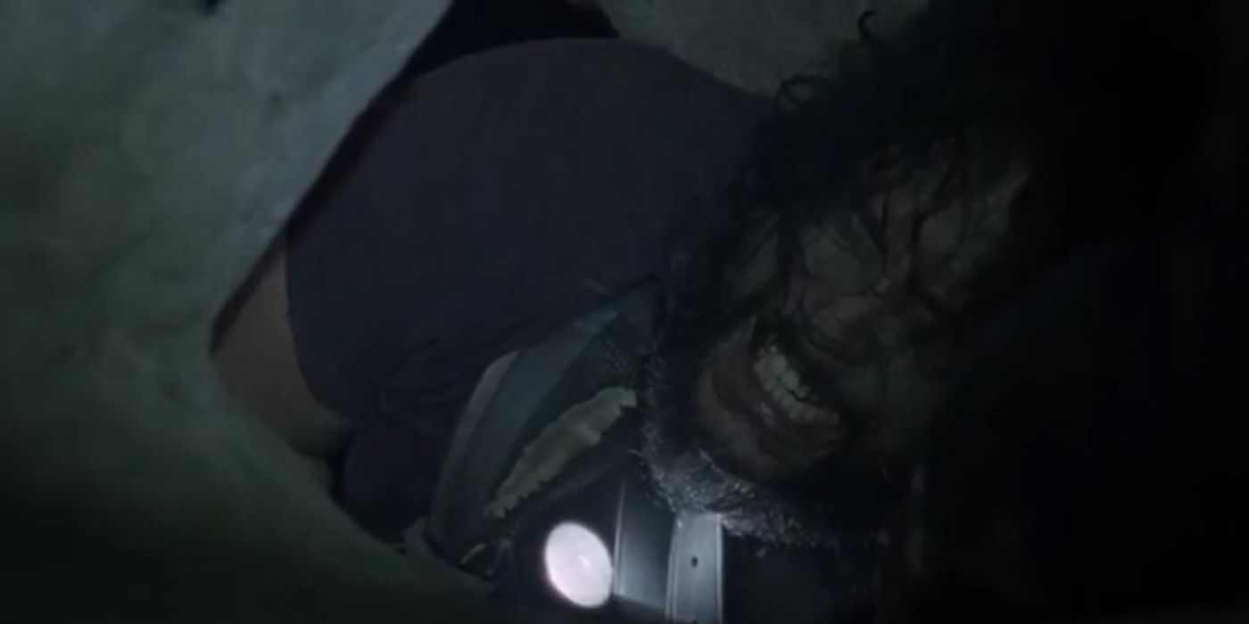 Jerry trying to squeeze out of a small, dark hole in a cave in The Walking Dead.